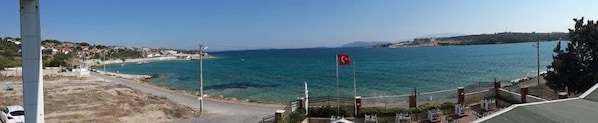 Vista costera con cielo despejado, una bandera y una carretera que lleva a una playa.