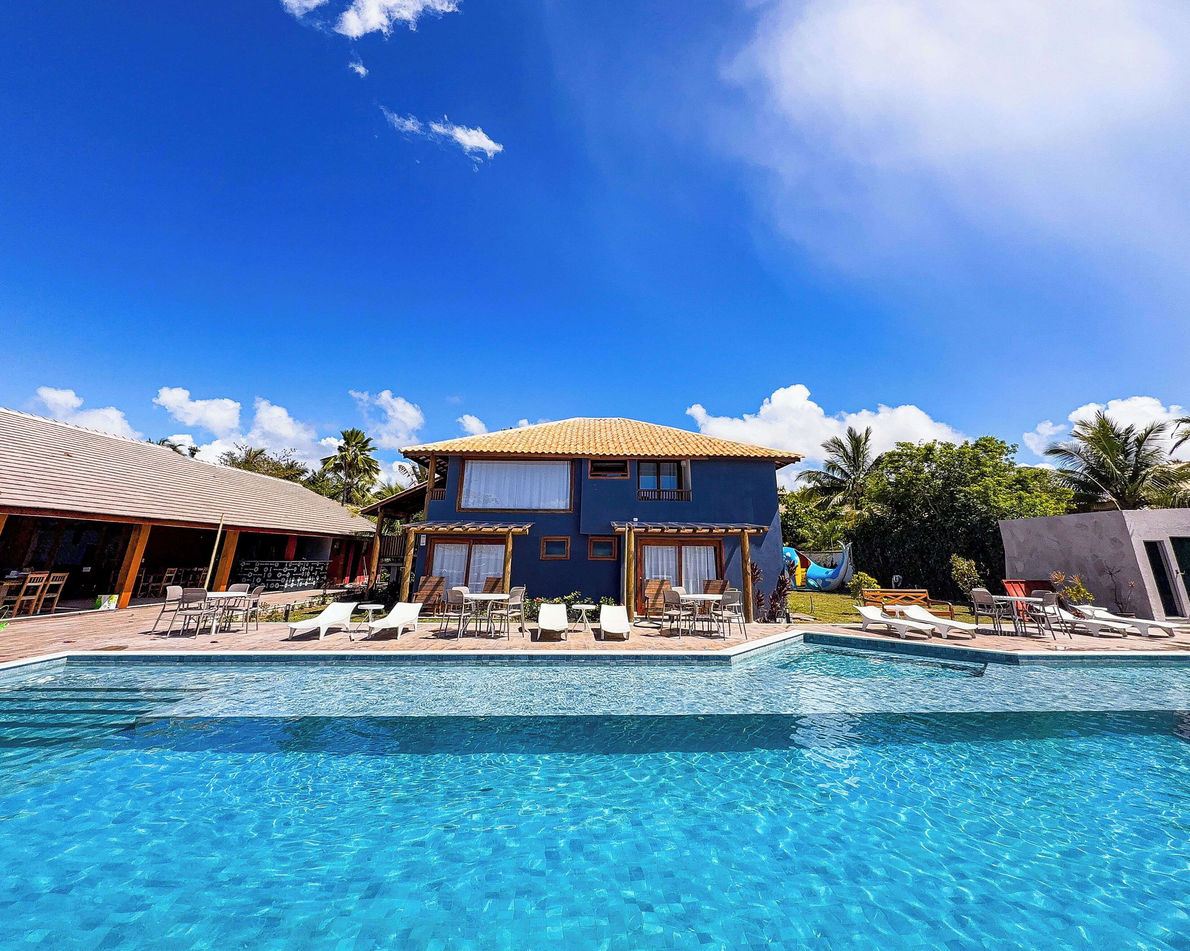 A pool area with lounge chairs and a building with a tiled roof.