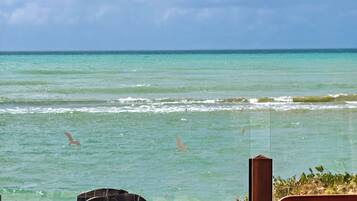 A wooden deck overlooking turquoise waters with a view of the sea and sky.