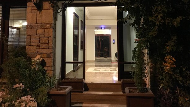 A hotel entrance with a stone facade, a glass door, and a small set of steps leading to an elevator. - Lacin Apart Otel (Datça)