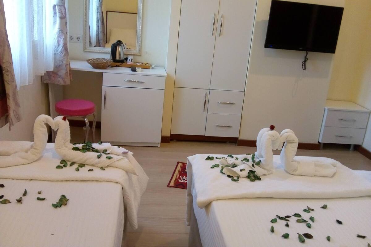 A hotel room with two beds, a desk, a mirror, a television, and a wardrobe.