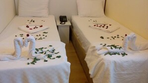 Two single beds with white linens, each adorned with a swan towel art and scattered rose petals. - Lacin Apart Otel (Datça)
