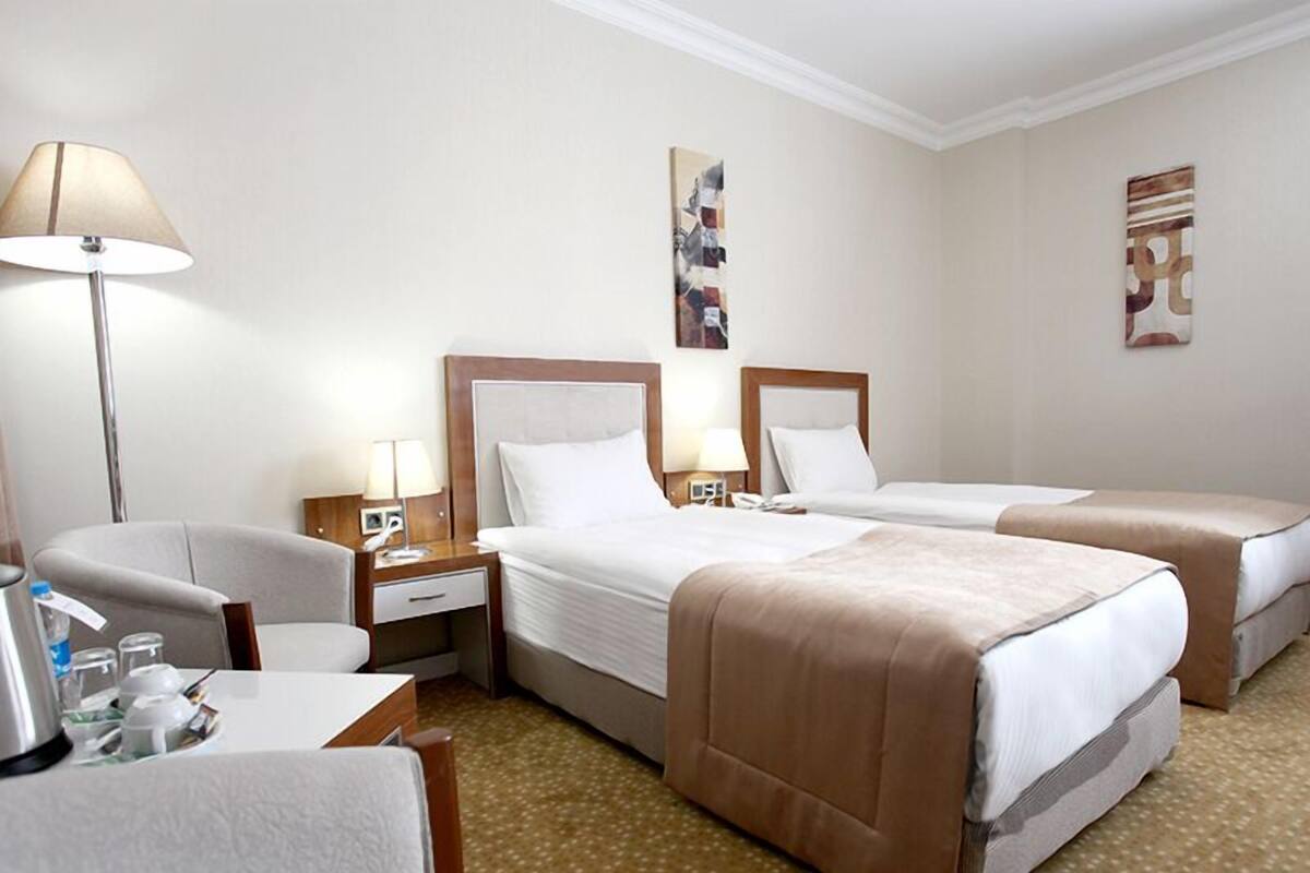 Una habitación de hotel con dos camas, un escritorio, una silla y una lámpara.