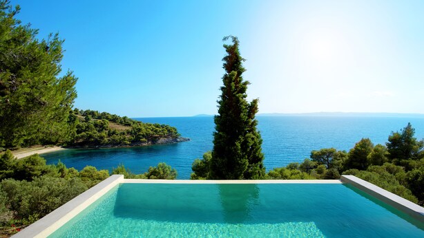 Une piscine d’un bleu éclatant, avec vue sur la mer et la végétation environnante.