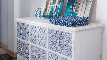 A white cabinet with blue and white patterned tiles and two framed pictures on top.
