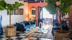 A living room with a checkered floor, a blue sofa, and two large potted plants. - Apolline Martinique (Fort-de-France)