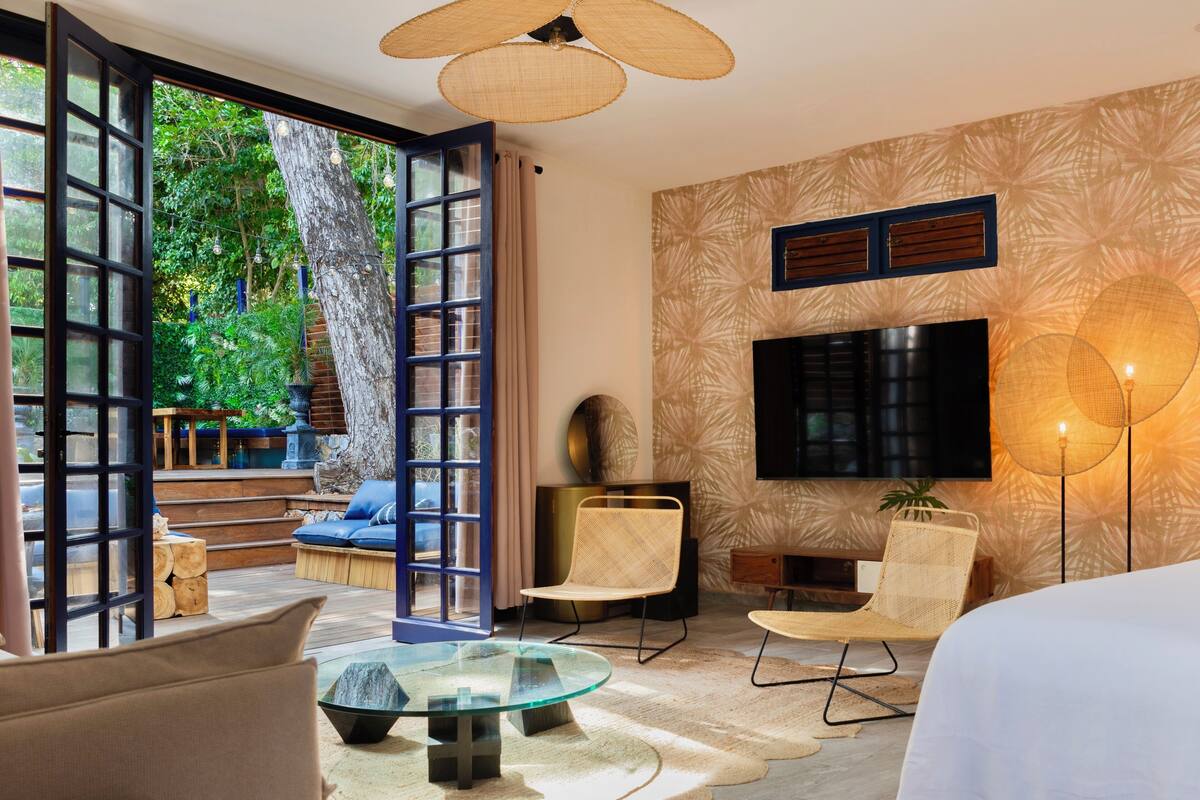 A modern living room with a glass coffee table, a sofa, and a TV mounted on the wall.