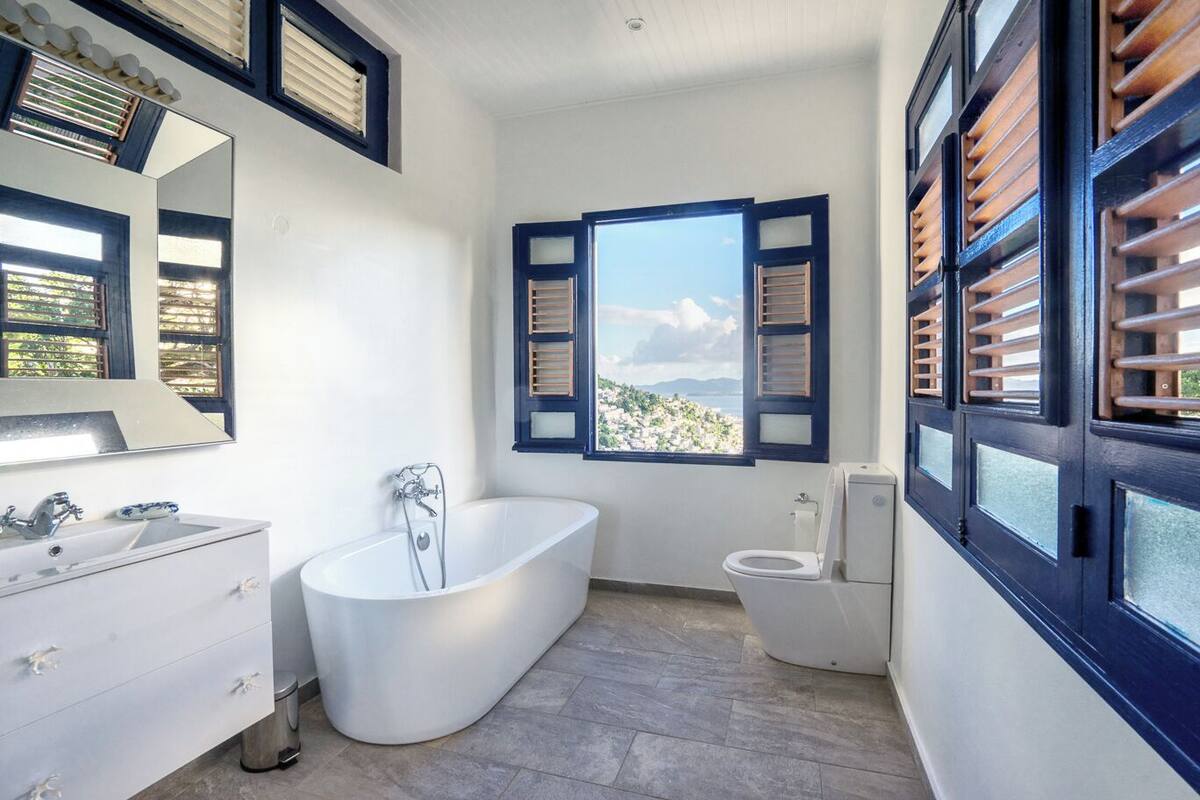 A modern bathroom with a freestanding bathtub, a toilet, and a large mirror.