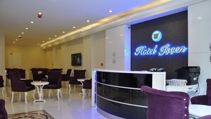 Zona de recepción de hotel con un mostrador curvo, sillas tapizadas en color morado y una decoración de diseño moderno.