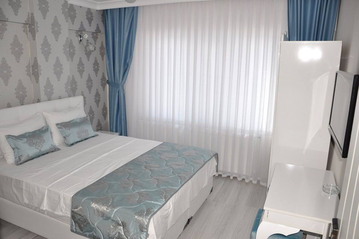 Un dormitorio con cama, cortinas, televisor y armario.