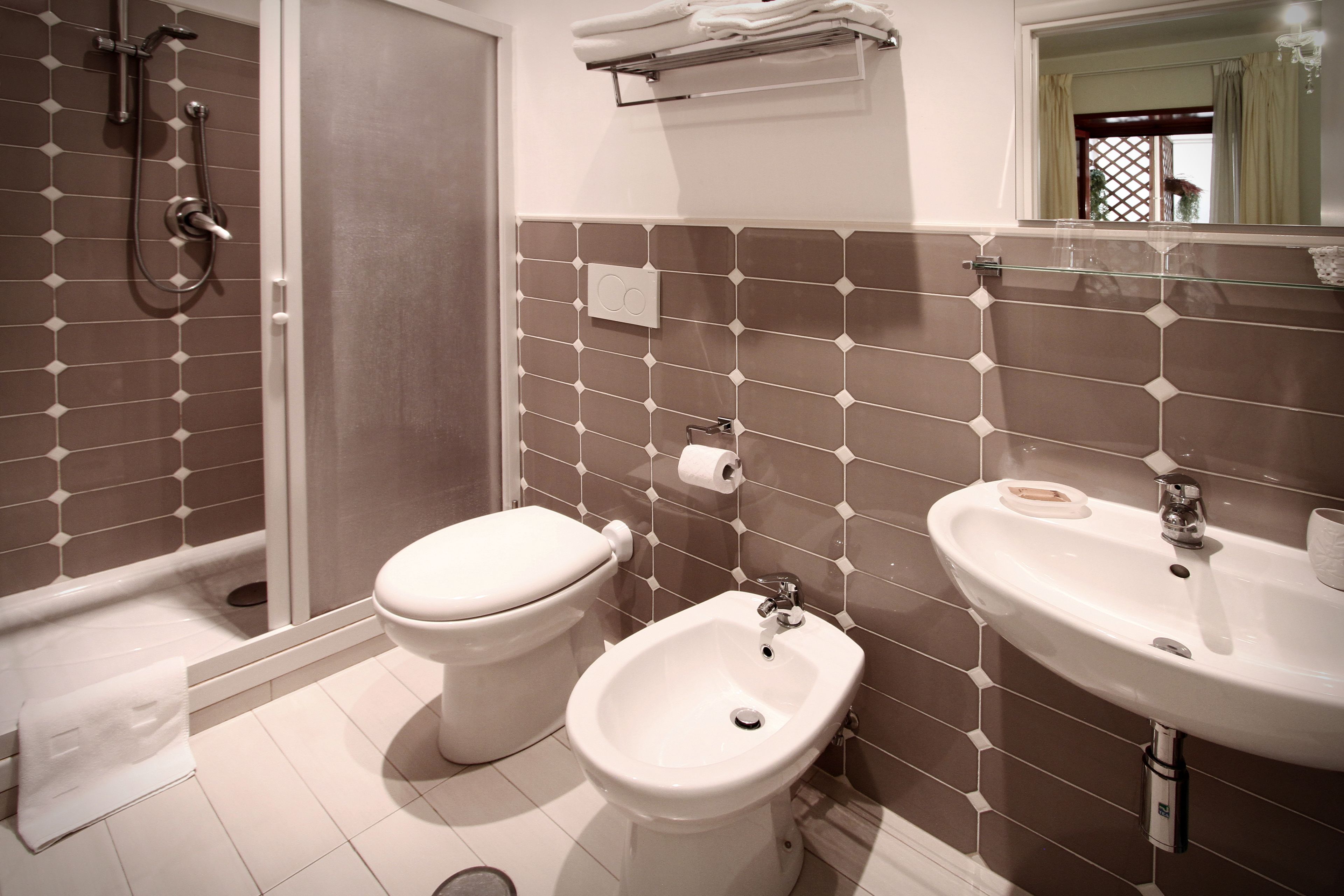 Ein Badezimmer mit Dusche, Toilette, Bidet, Waschbecken und Handtuchhalter.