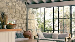 A cozy room with a stone wall, a wooden bench, a sofa, and a large window with a view of greenery. - Manastir Alacati Hotel (Cesme)