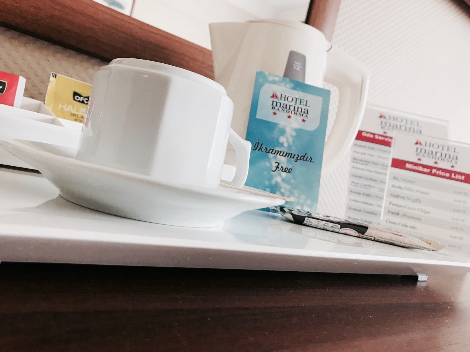 Bandeja de hotel con una taza blanca, una caja de pañuelos y un menú.
