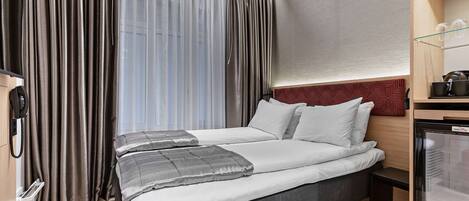 A hotel room with a bed, curtains, a TV, a small table, and a microwave.