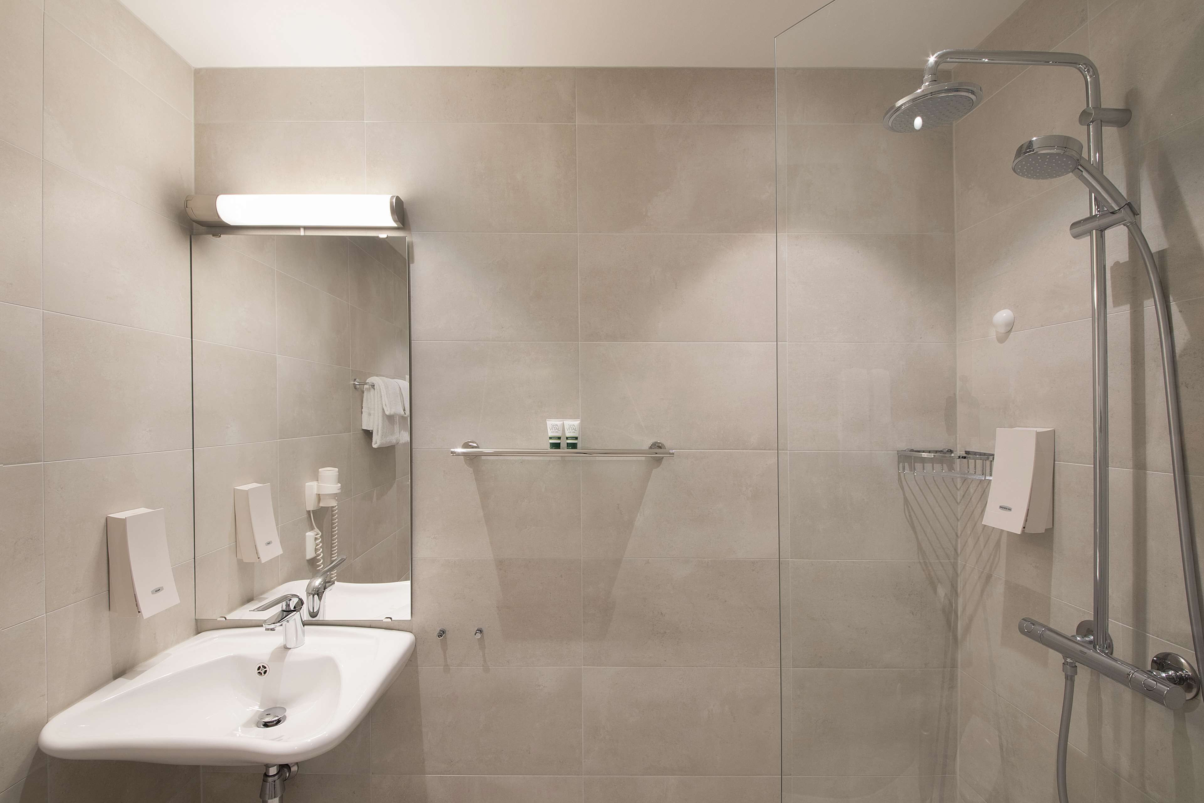 A modern bathroom with a sink, mirror, and shower.