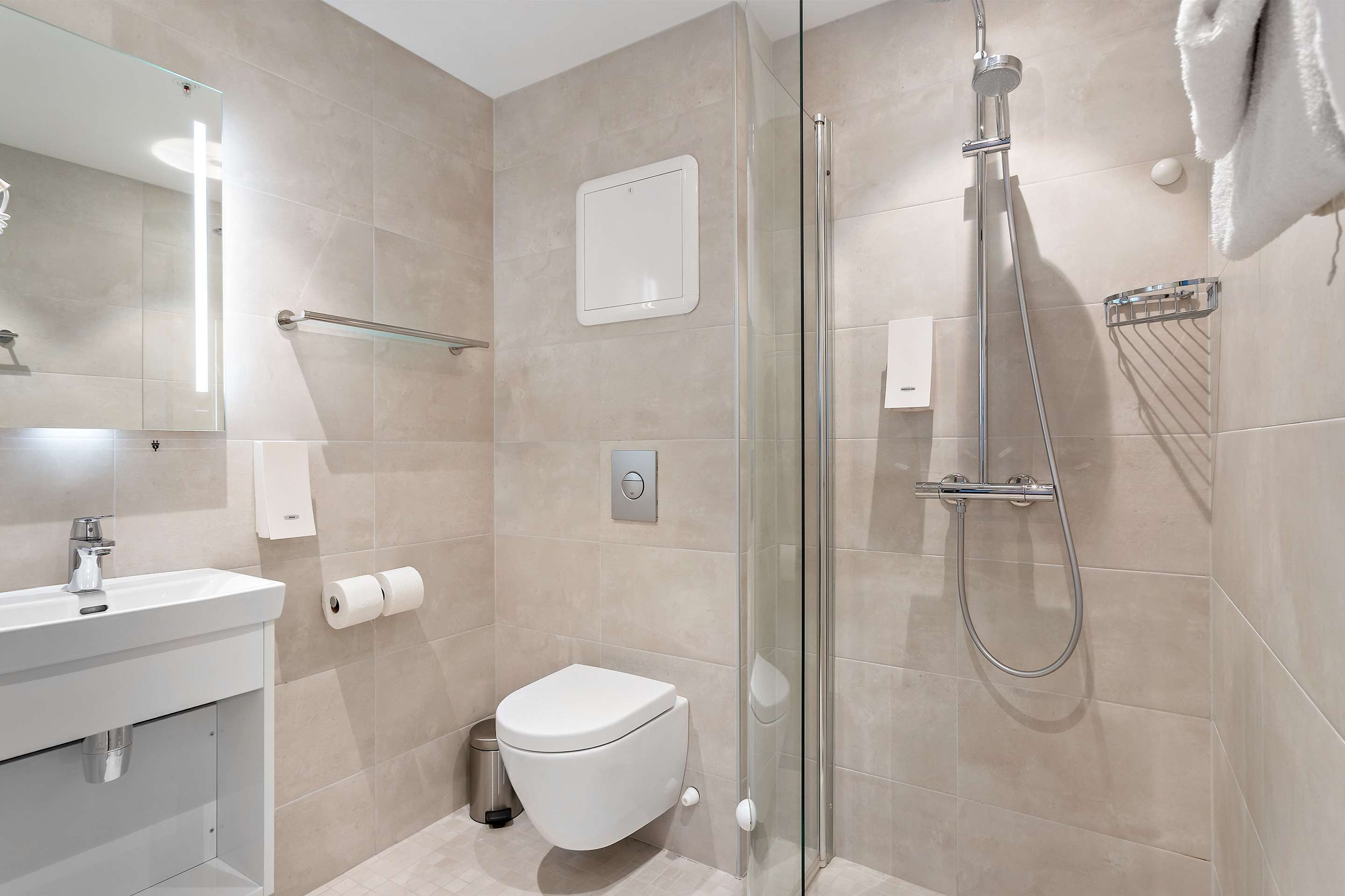 Une salle de bain moderne avec une douche à parois de verre, un lavabo blanc et des toilettes.