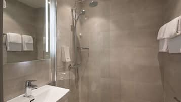 A modern bathroom with a glass-enclosed shower, a white sink, and a large mirror.