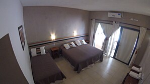 Une chambre d’hôtel avec deux lits, une petite table, une chaise et un appareil de climatisation.