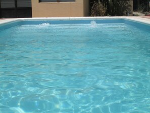 A swimming pool with clear blue water and a tiled edge.