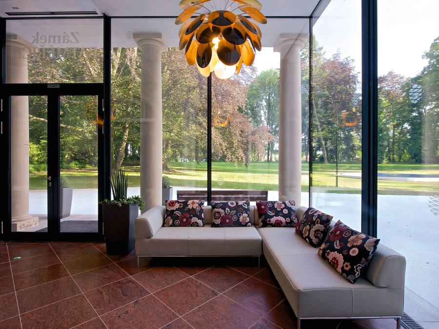 A modern lobby with a seating area, large windows, and a unique ceiling light fixture.