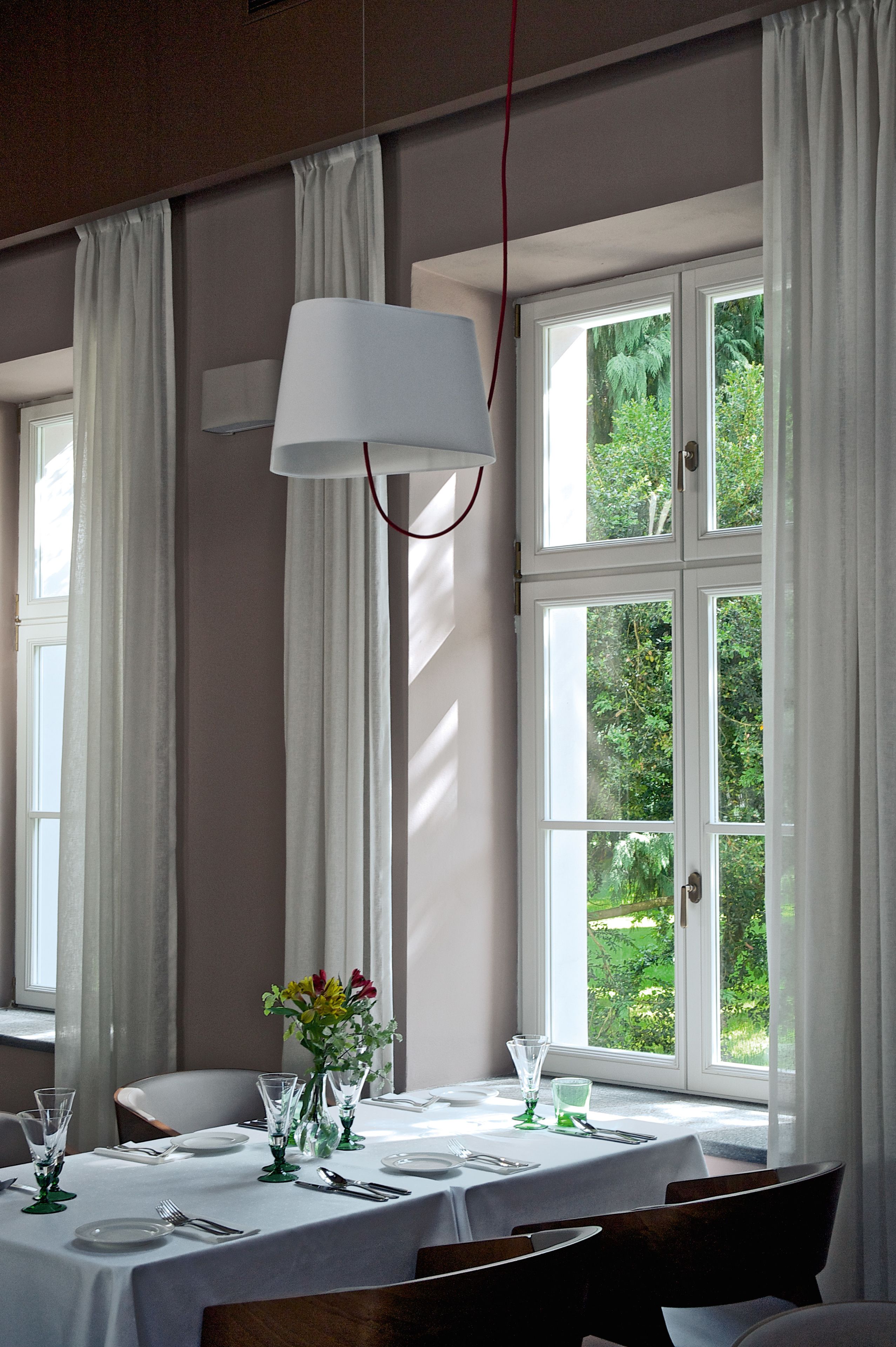 A dining area with a table set for four, large windows, and a hanging light fixture.