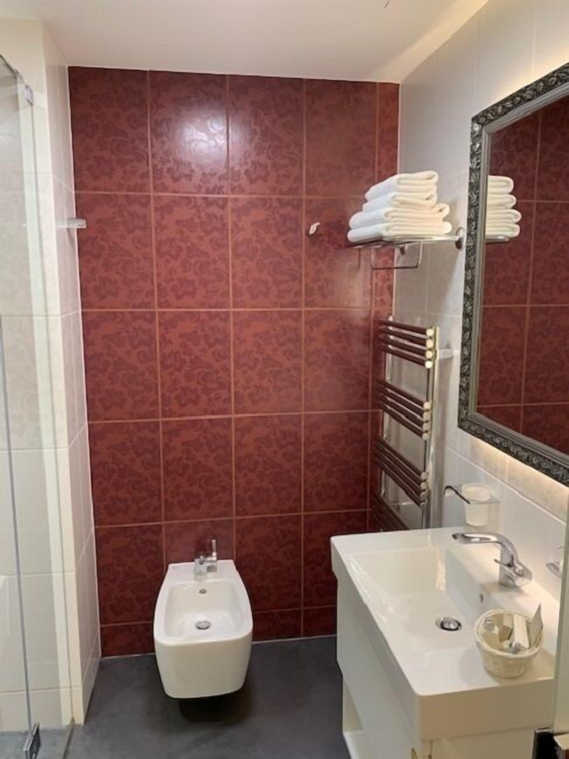 Une salle de bain équipée d’un bidet, d’un lavabo, d’un miroir et d’un porte-serviettes.