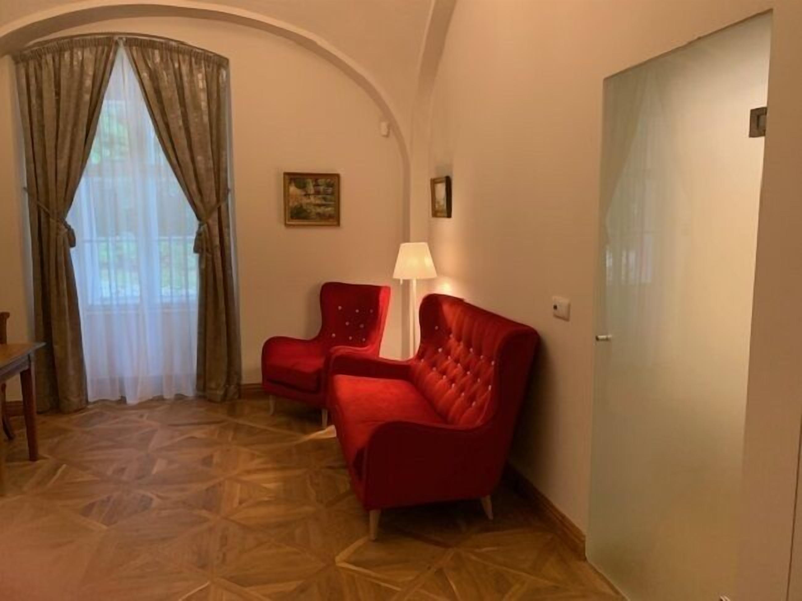 Una habitación con suelo estampado, un sofá rojo, una lámpara y un cuadro en la pared.