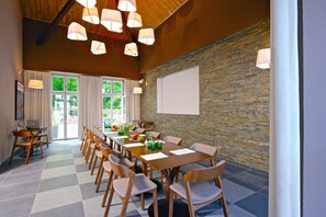 A conference room with a long table, chairs, a projector screen, and a stone wall. - Zámek Ratměřice Hotel & Resort (Ratmerice)
