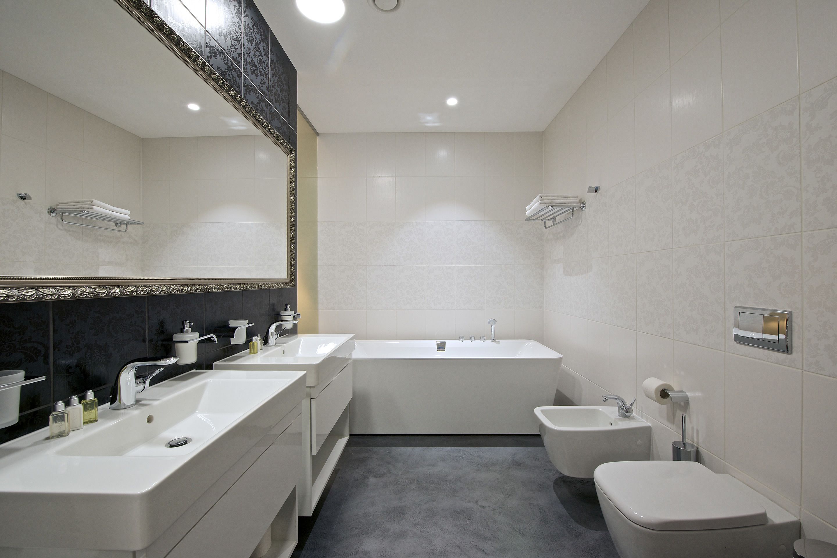 Une salle de bain moderne avec une grande baignoire, deux lavabos, un bidet et des toilettes.