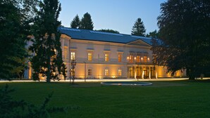 A large, classical building with a symmetrical facade, a central entrance, and a well-maintained lawn in front.