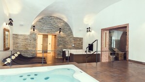 A spa area with a hot tub, stone walls, and a seating area with a fireplace.