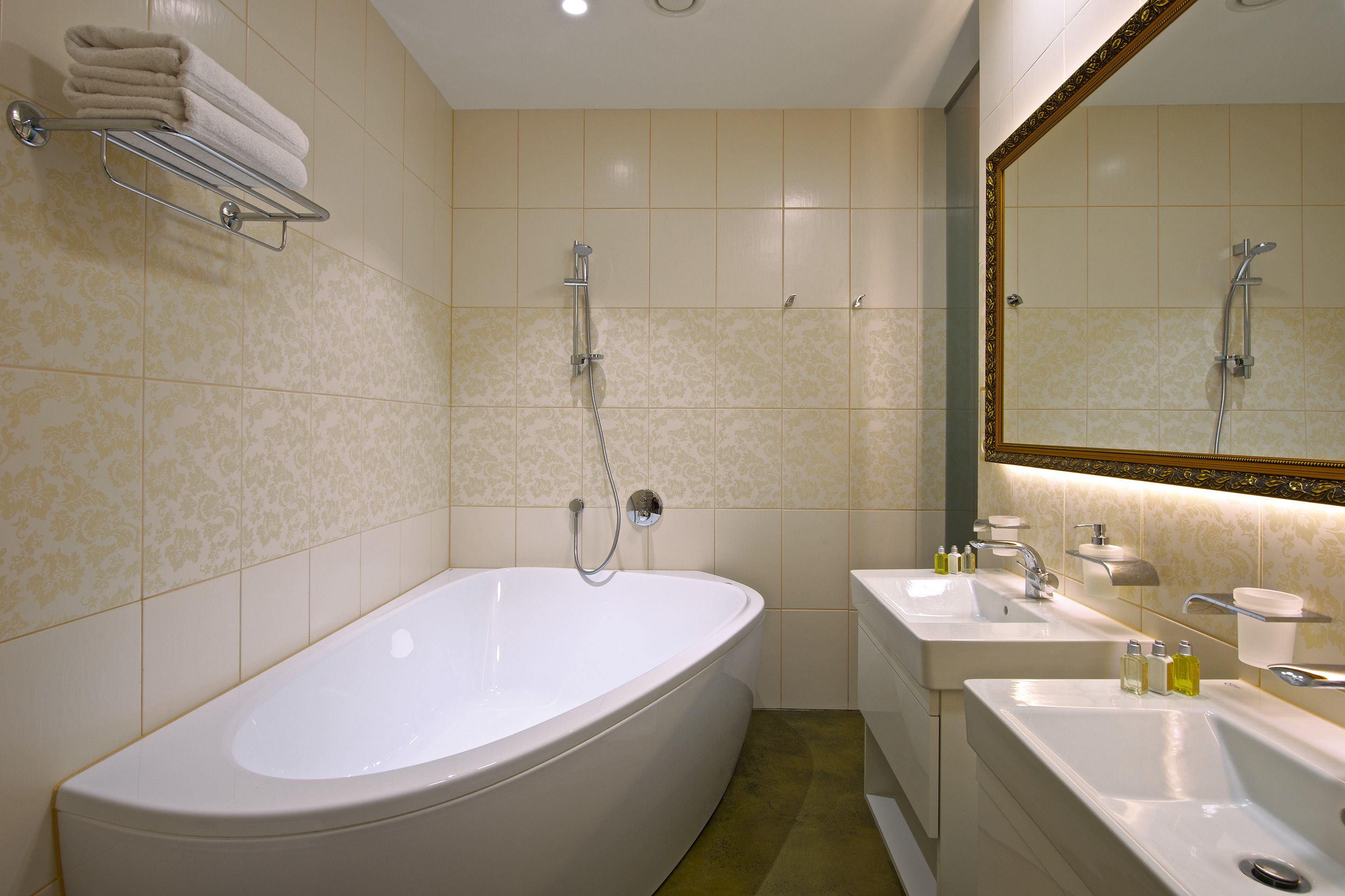 Un baño con una bañera grande, dos lavamanos y un espejo con marco decorativo.