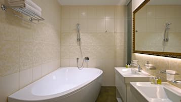 Un baño con una bañera grande, dos lavamanos y un espejo con marco decorativo.