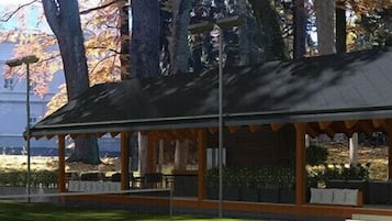 Ein Tennisplatz mit überdachtem Pavillon, umgeben von Bäumen.