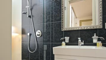 A modern bathroom with a glass-enclosed shower, a white vanity, and a large mirror with an ornate frame.