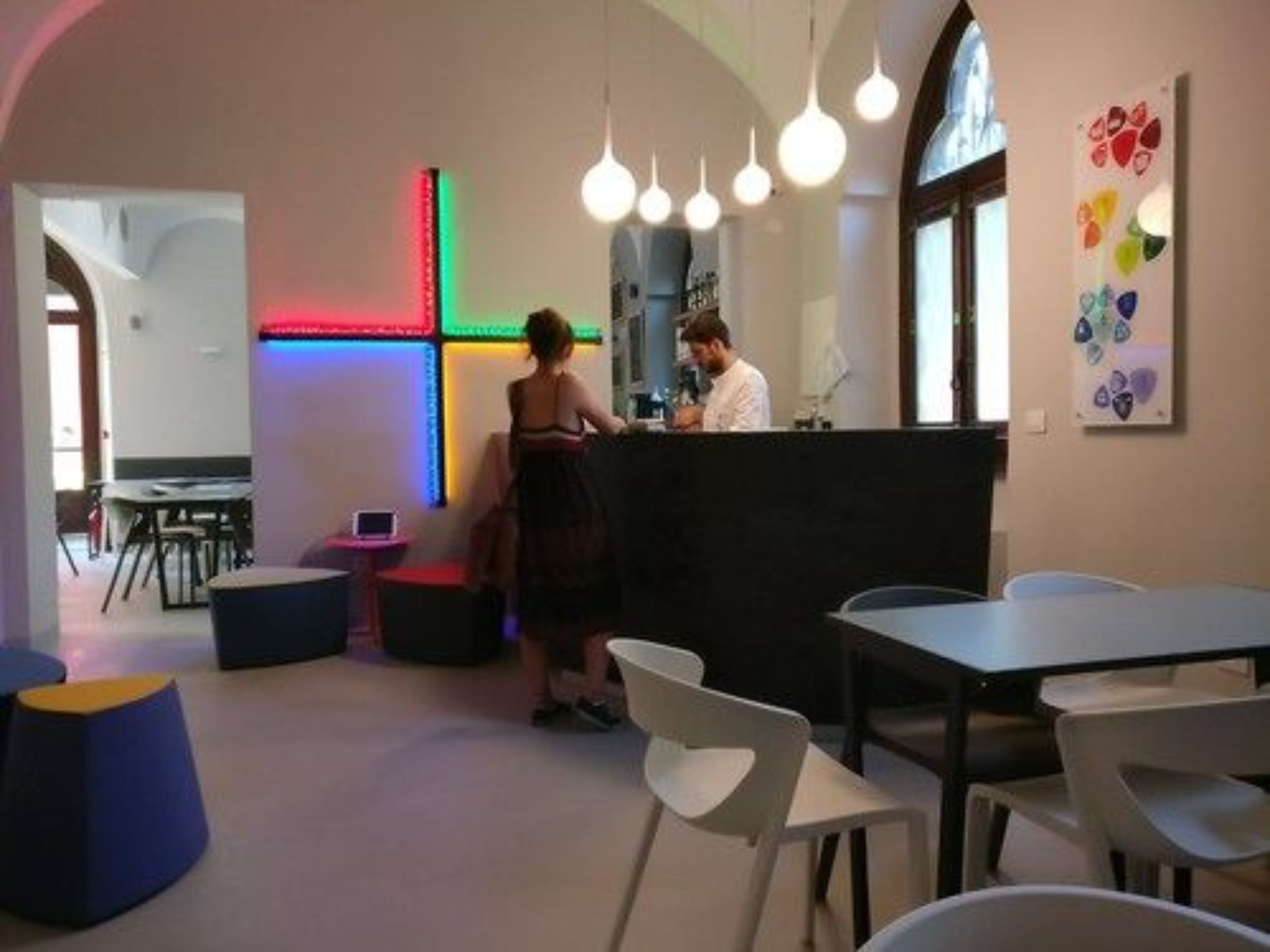 Un interior moderno con mostrador de recepción, zona de estar y coloridas obras de arte en la pared.