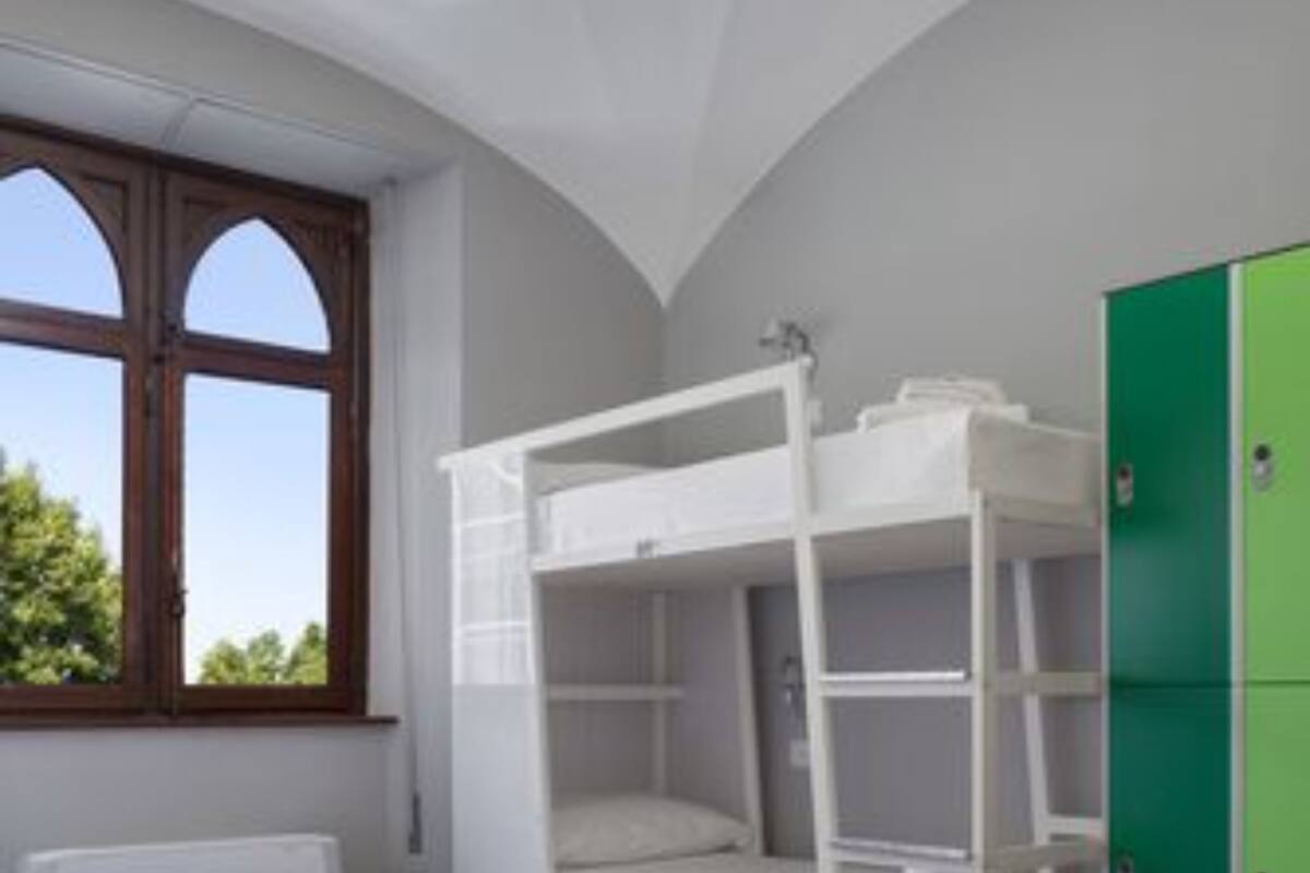A bunk bed room with a large window, a green cabinet, and a blue ottoman.