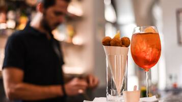 Une table avec une boisson et un plat, une personne à l’arrière-plan et un coin bar.