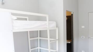 A bunk bed in a room with a wooden floor and a white door.
