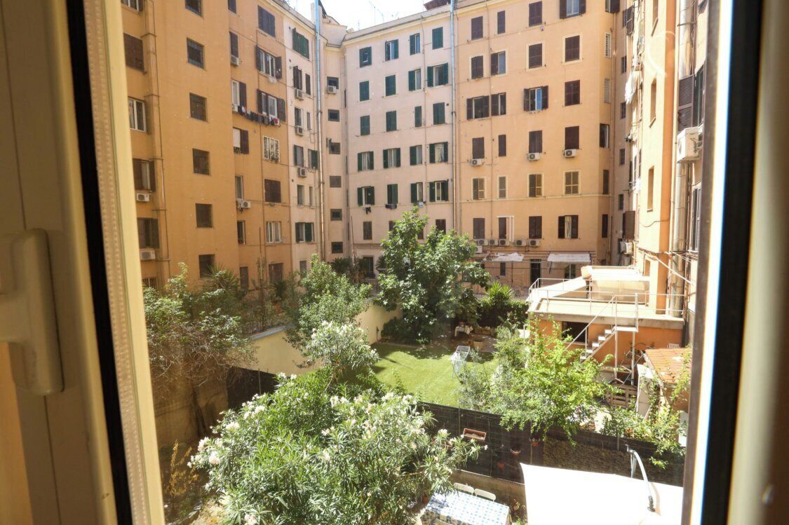 A courtyard with multiple apartment buildings, a small garden area, and a staircase leading to an upper level.