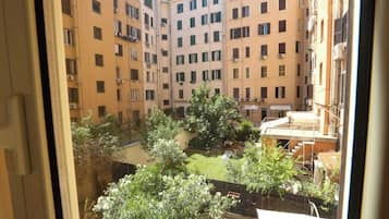A courtyard with multiple apartment buildings, a small garden area, and a staircase leading to an upper level.