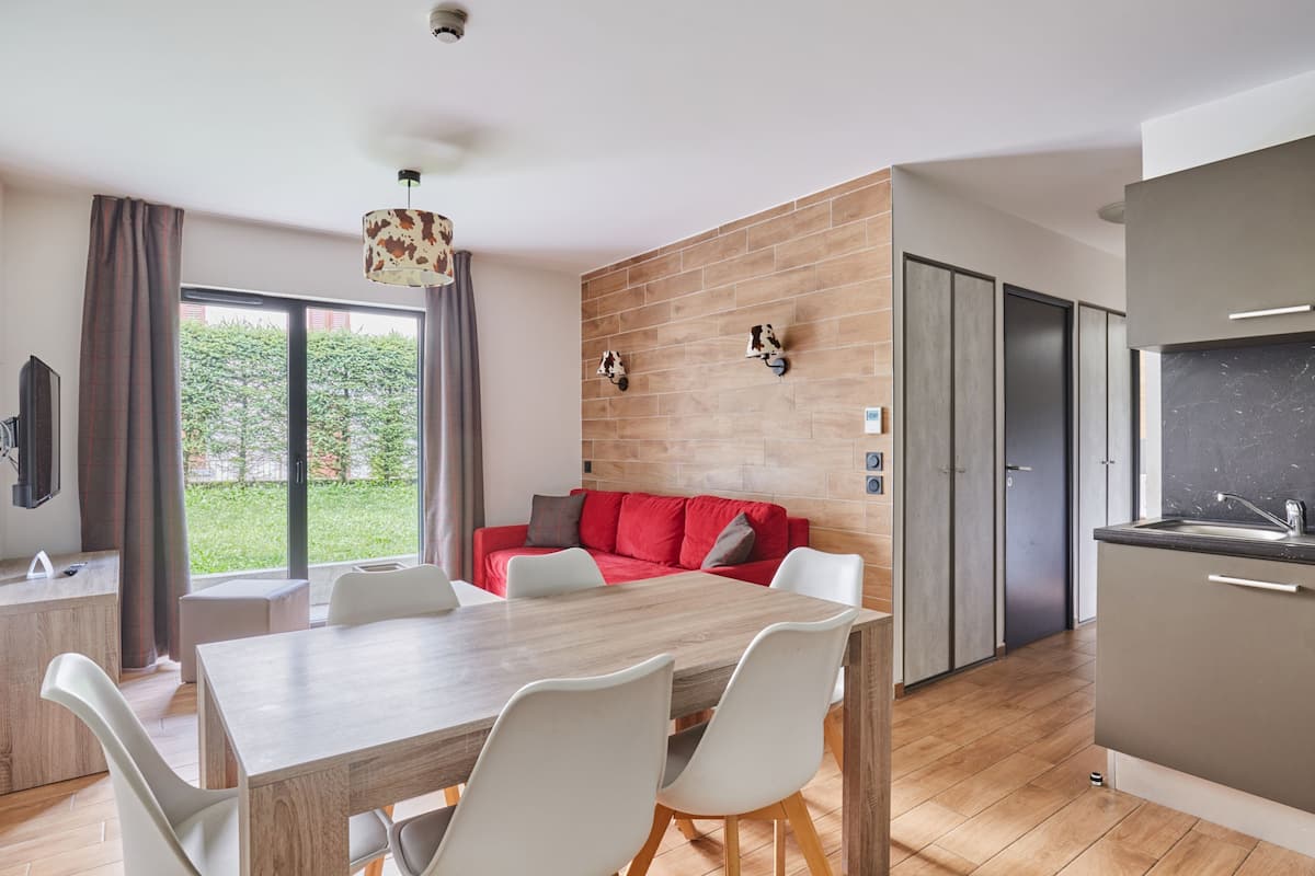 A modern kitchen with a marble countertop and a dining area with a wooden table and white chairs.
