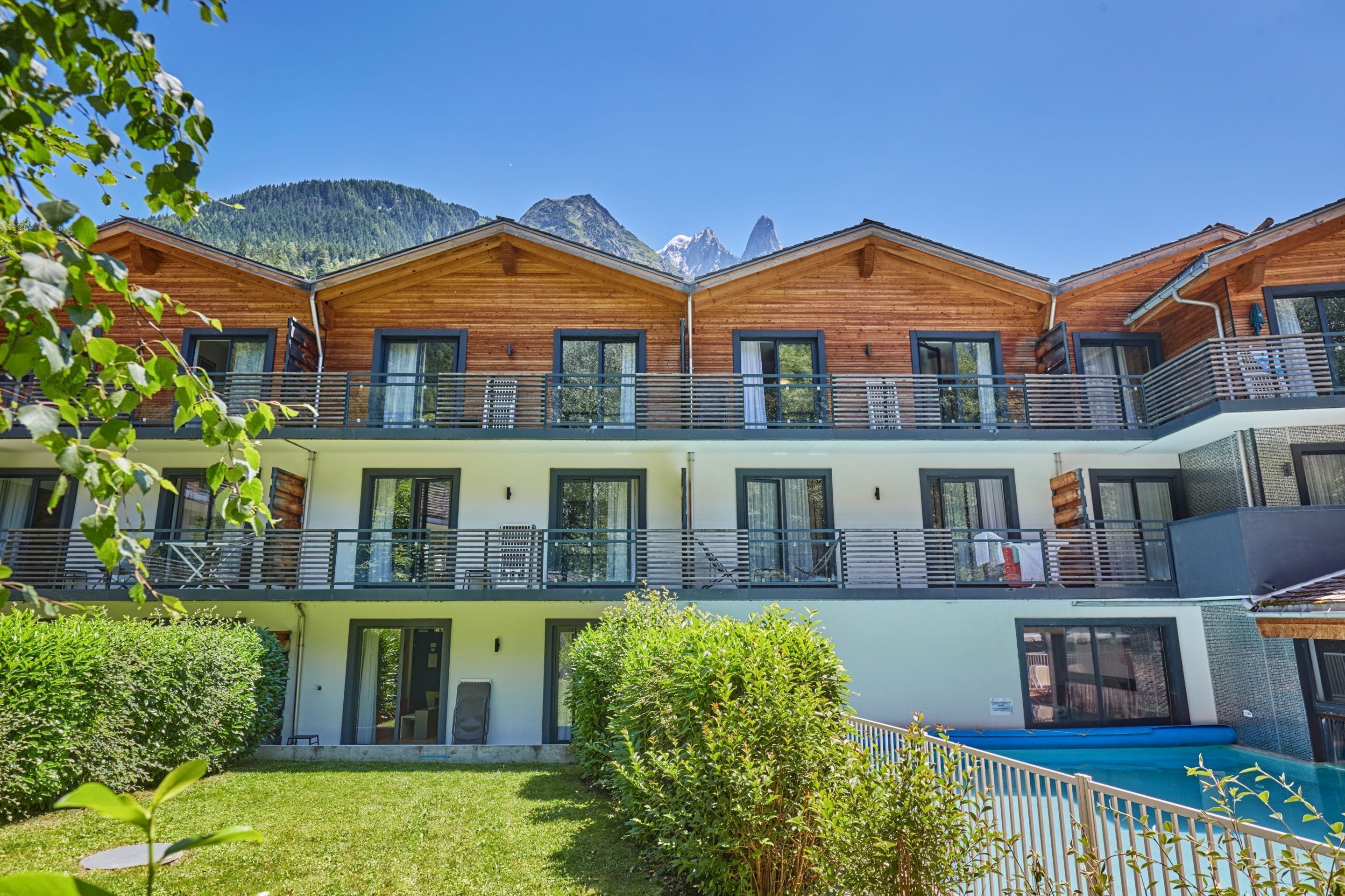 Un hôtel comprenant plusieurs chalets en bois, des balcons et une piscine.