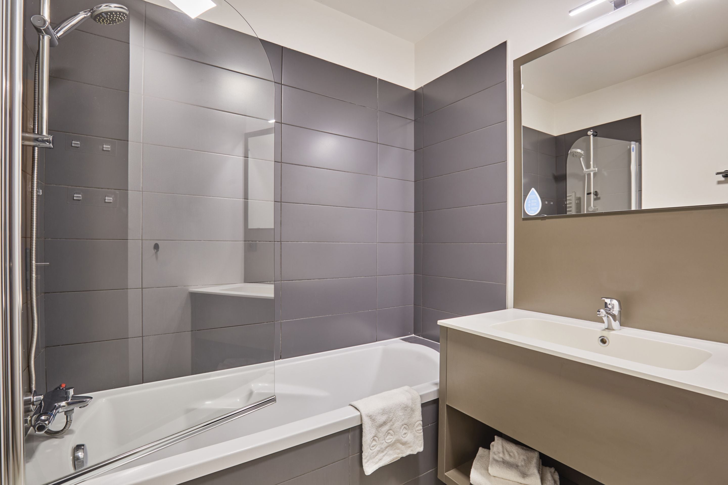 A modern bathroom with a bathtub, a sink, and a large mirror.