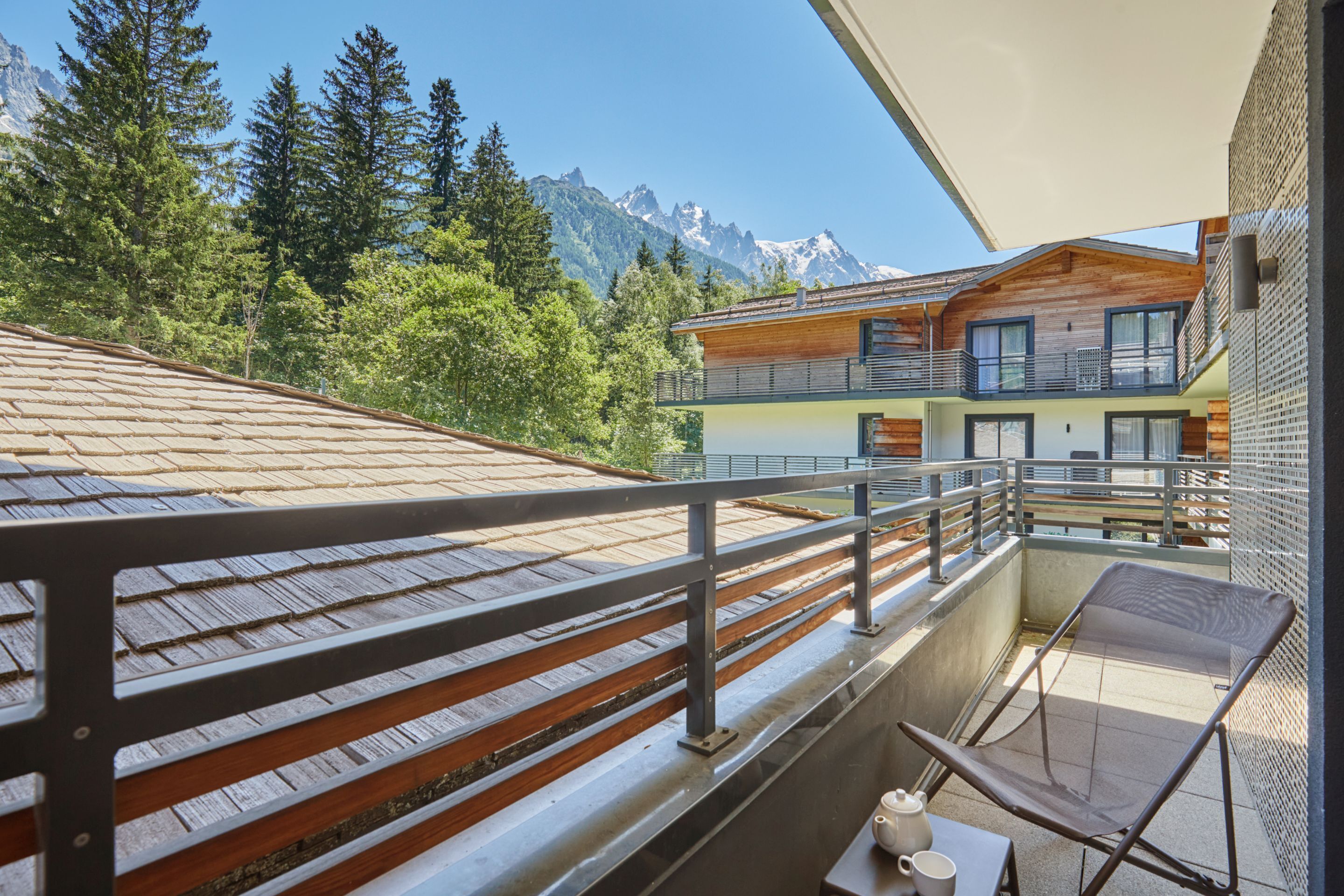 A balcony with a wooden floor, metal railing, and a table with a cup and saucer.