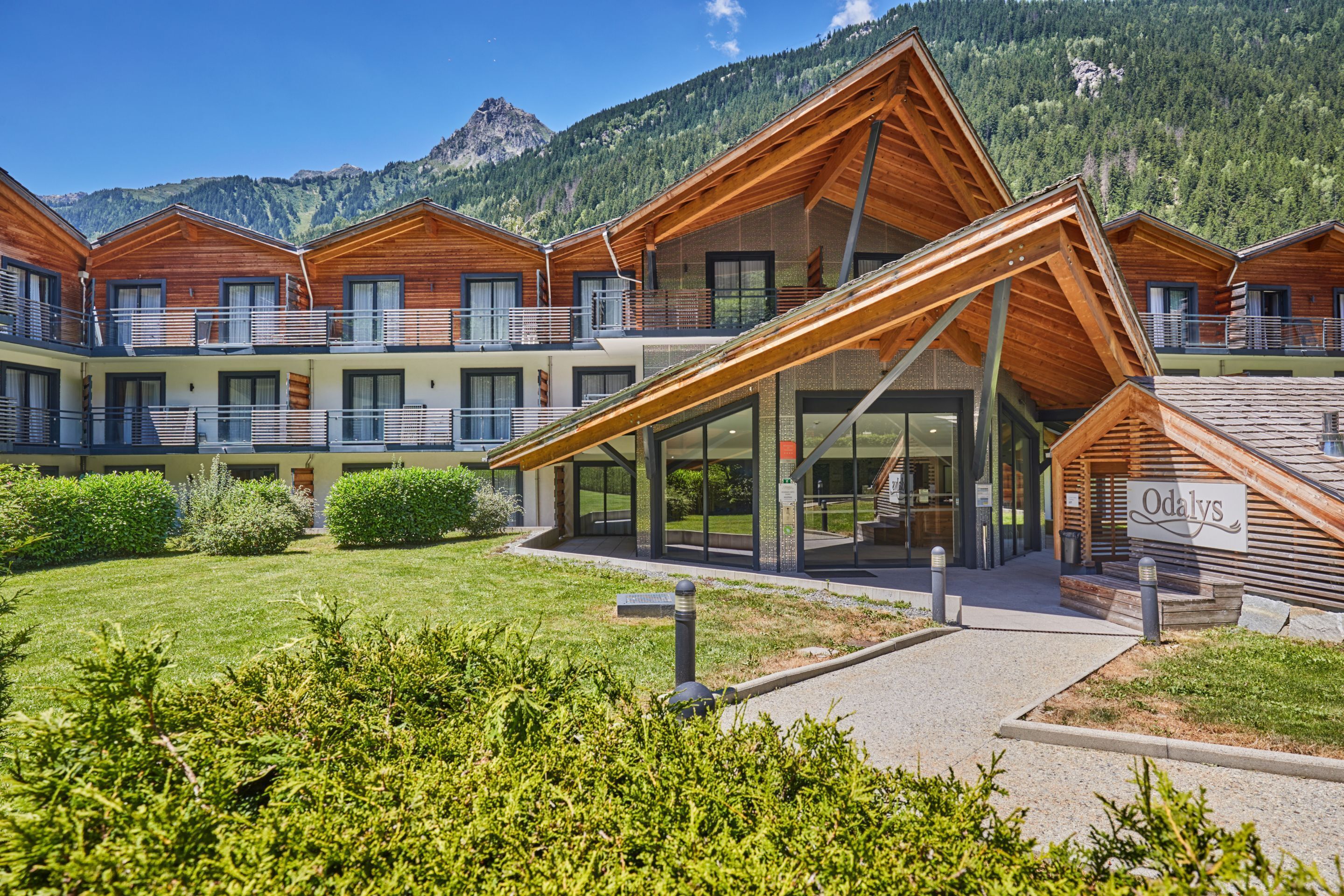 A hotel with a modern design, featuring a prominent glass entrance and wooden exterior.