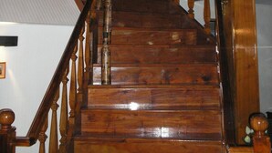 A wooden staircase with a handrail and a chandelier. - Amparo Hosteria (Neuquén)