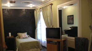 A bedroom with a bed, a television, a chair, and a mirror. - Amparo Hosteria (Neuquén)
