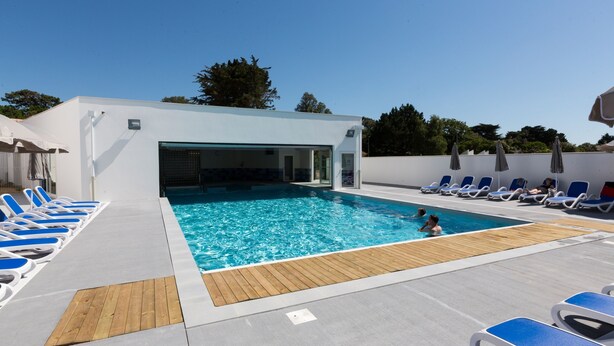 A pool area with blue lounge chairs and a wooden deck. - Résidence Odalys Domaine des Pins - Bois de la Chaise (Noirmoutier-en-l'Ile)