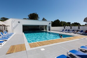 A pool area with blue lounge chairs and a wooden deck. - Résidence Odalys Domaine des Pins - Bois de la Chaise (Noirmoutier-en-l'Ile)